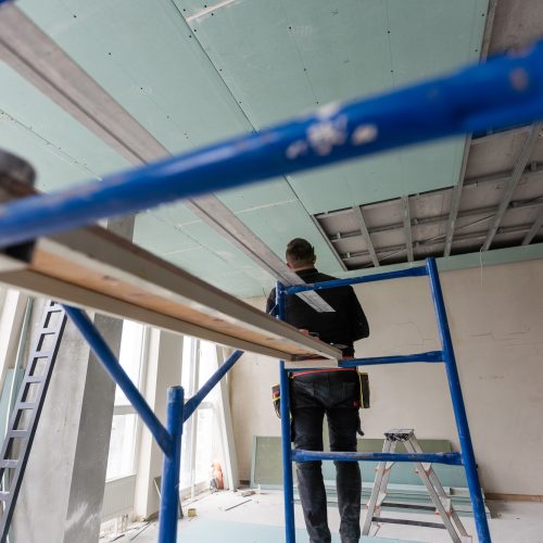 Drywall Installers. Men holding a gypsum board figured cut